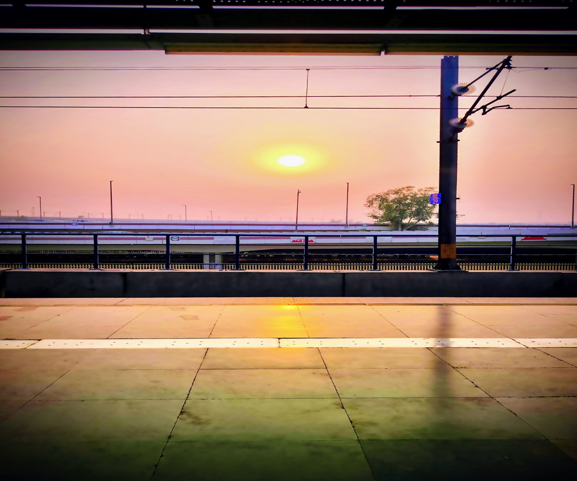 An empty railway station platform bathed in the warm, golden light of the setting sun, conveying a peaceful moment of stillness and quiet before the next journey.